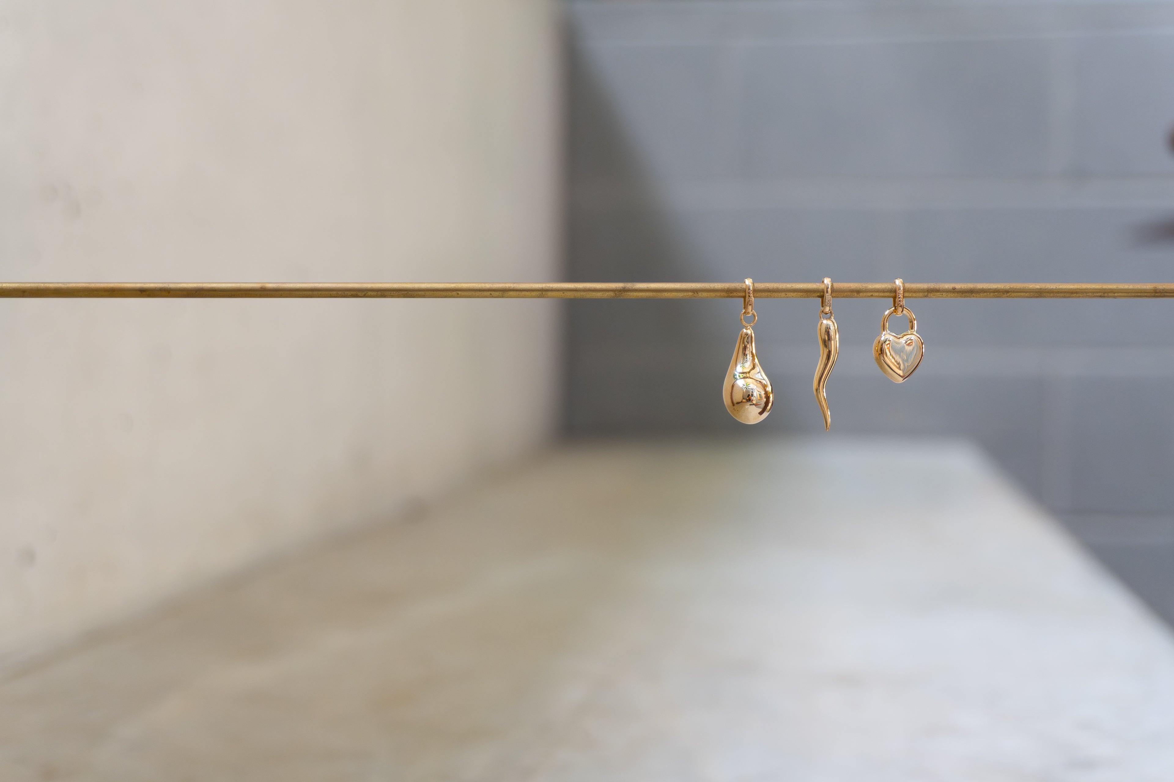 Three gold earrings on a stand with a blurred background