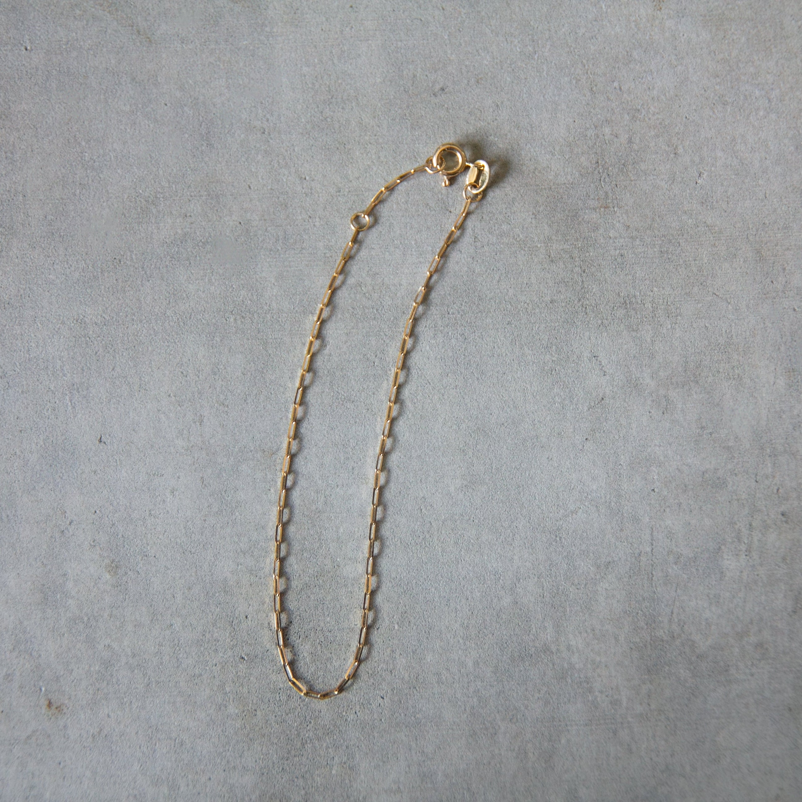 Gold chain necklace on a gray surface
